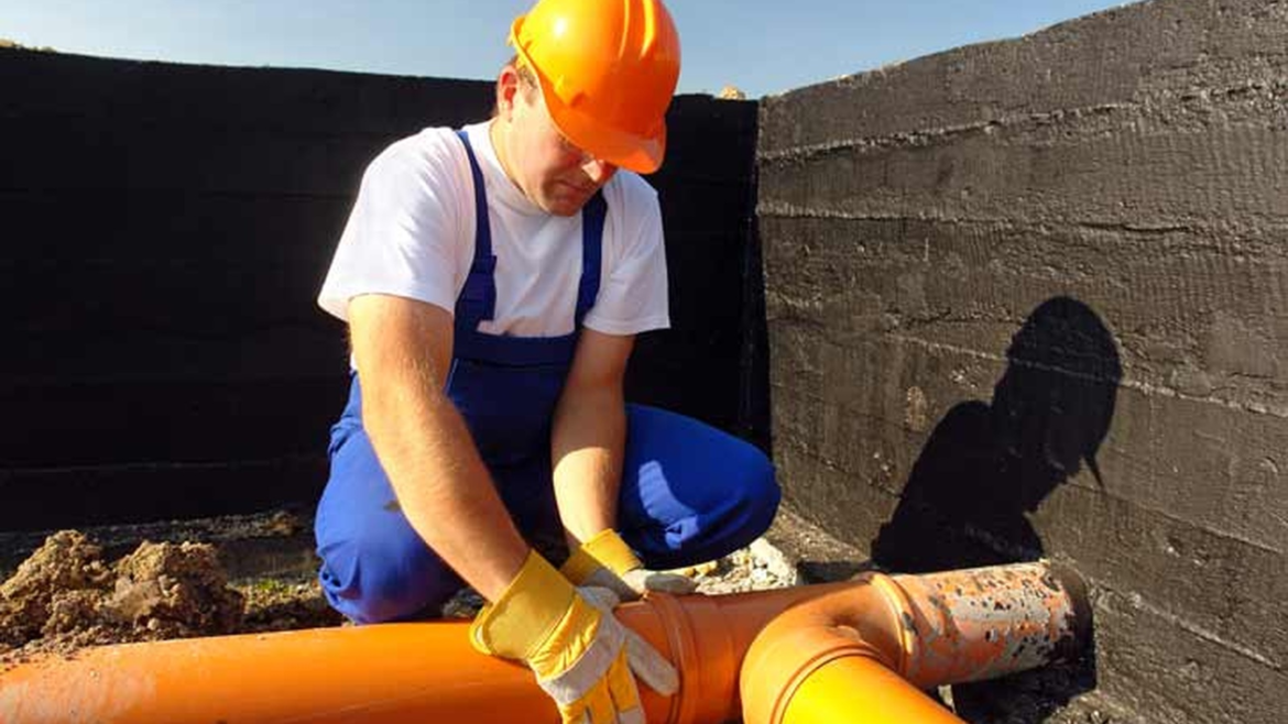 A drainage engineer working on exposed pipework. Image sourced from the Quick Clear Drainage website.
