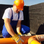 A drainage engineer working on exposed pipework. Image sourced from the Quick Clear Drainage website.